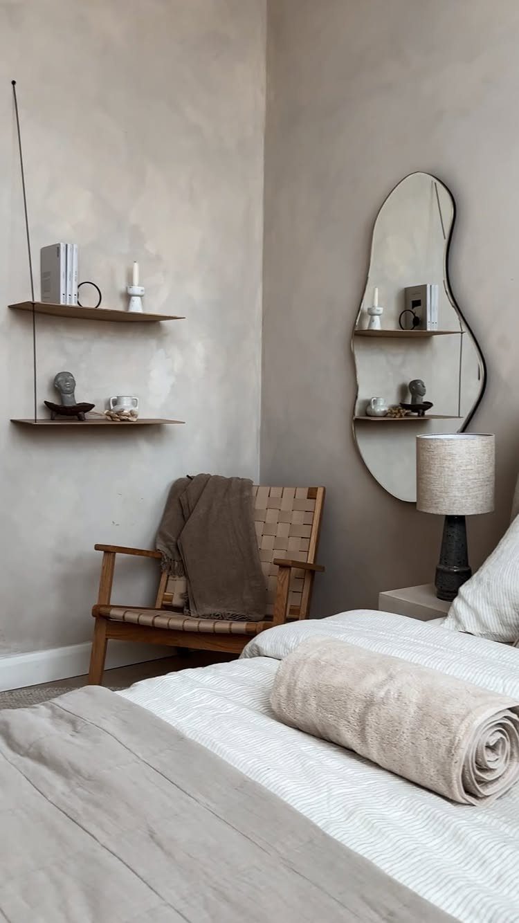 Wooden armchair with a brown throw blanket positioned in a cozy corner near a bed.