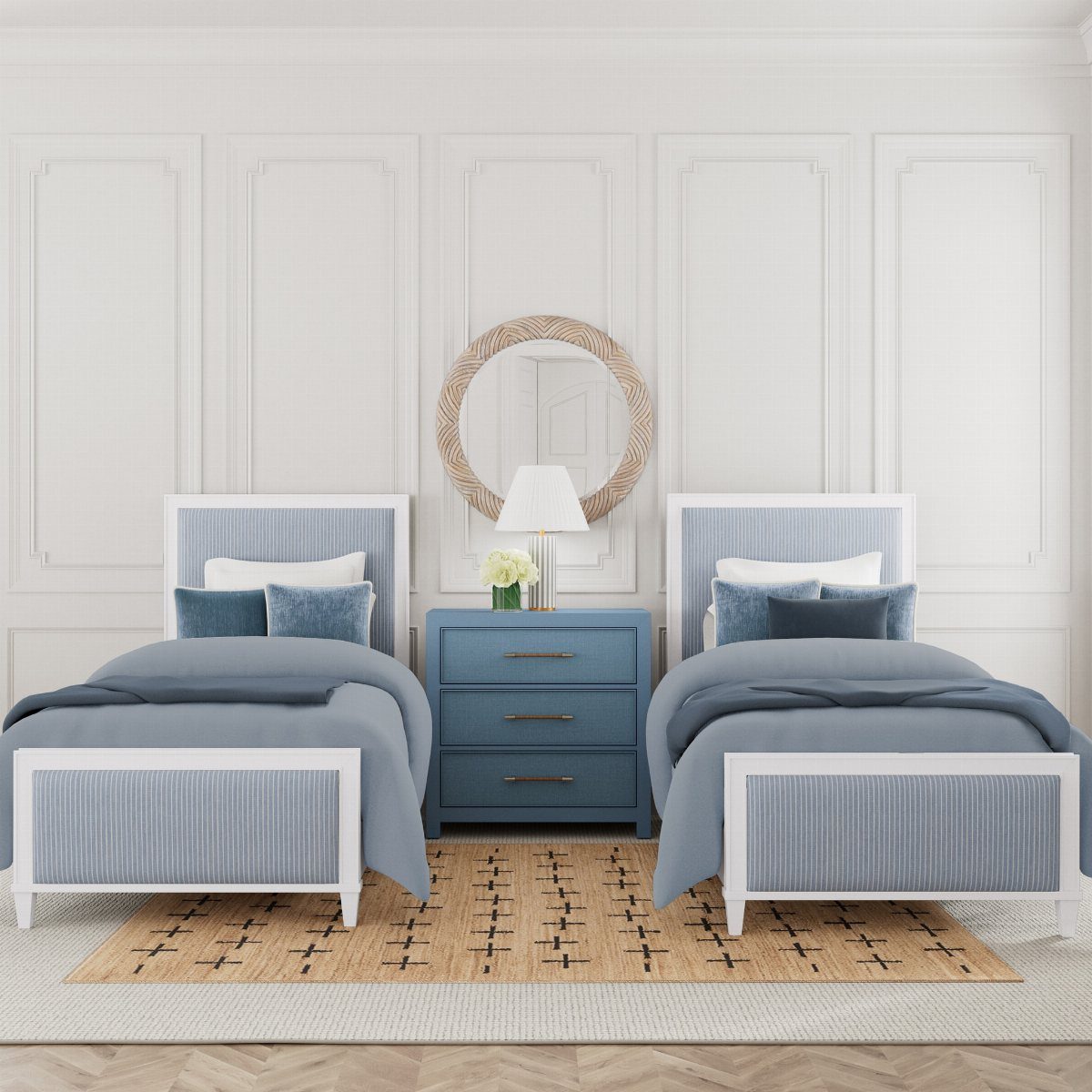 Two twin beds with blue bedding flank a blue nightstand in a white paneled room.