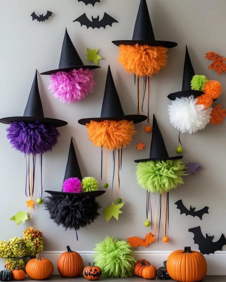 Colorful fluffy witch hat decorations hanging on a wall with black bats and pumpkins below.