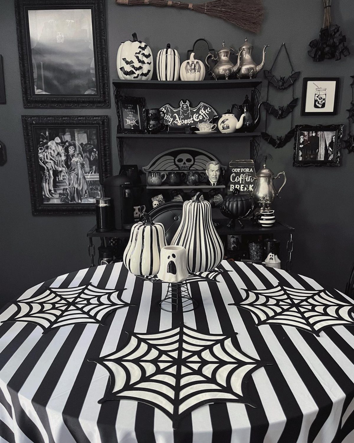 Black and white striped tablecloth with spiderweb patterns and striped pumpkins on a dining table.