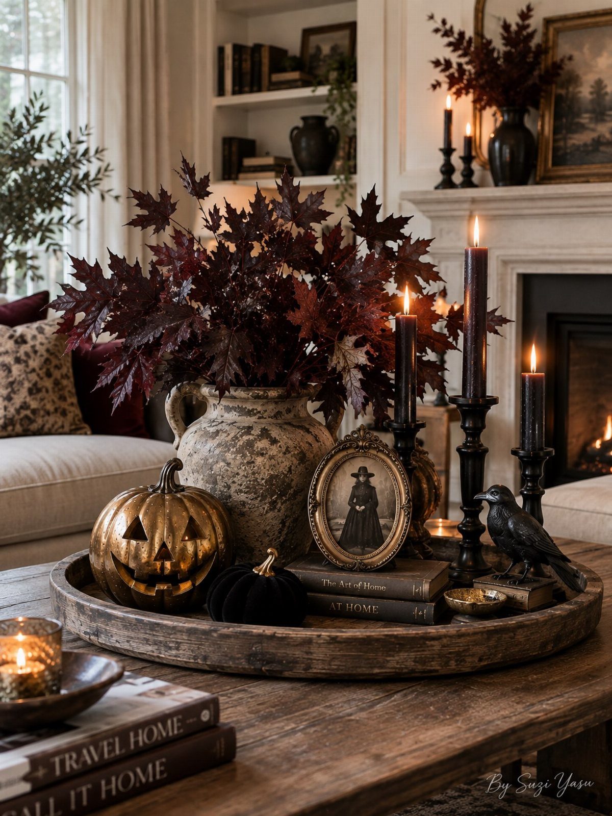 A decorative wooden tray featuring dark foliage, gold pumpkins, and black taper candles on a table.