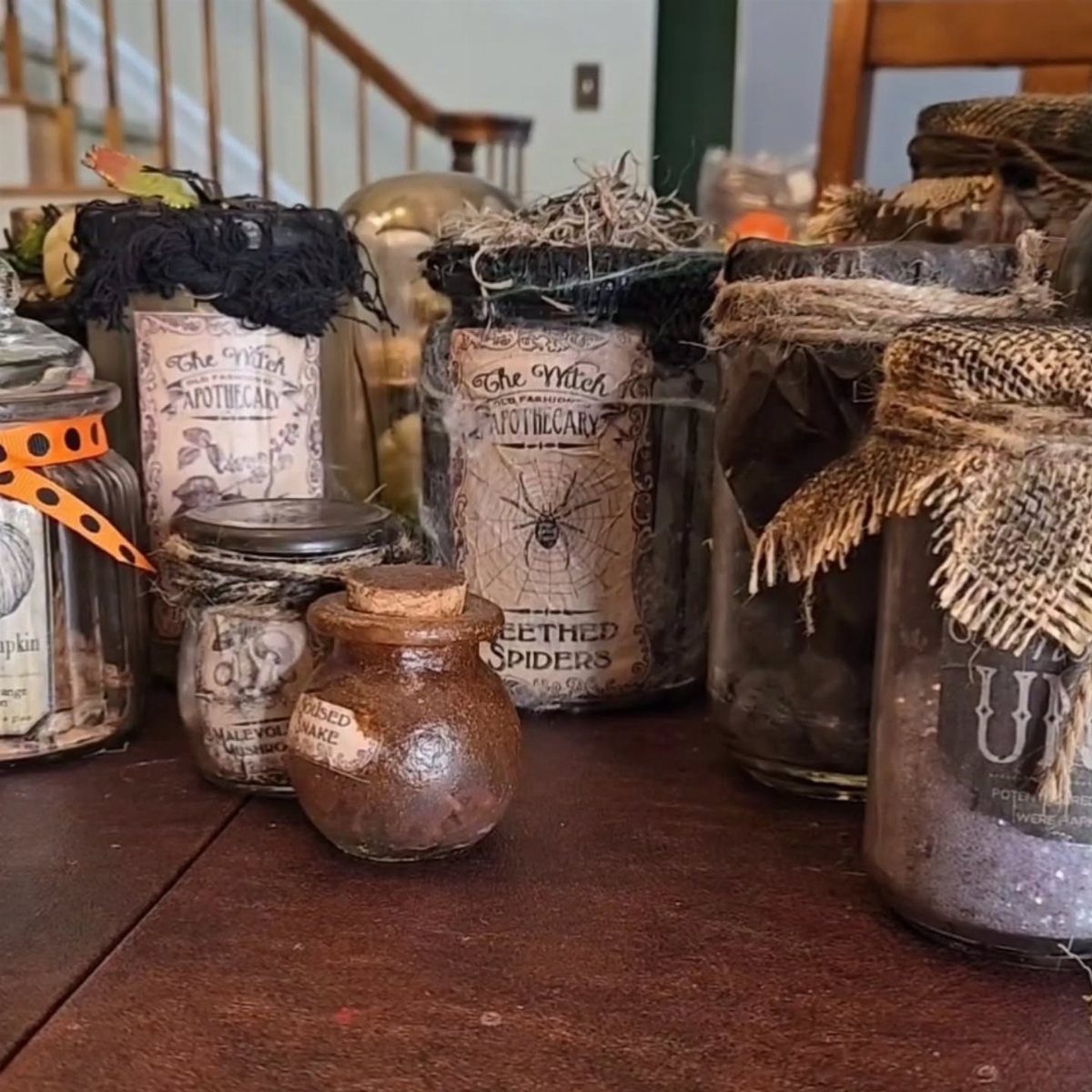 Vintage apothecary jars with spooky labels and textured decorations on a dark wooden table.