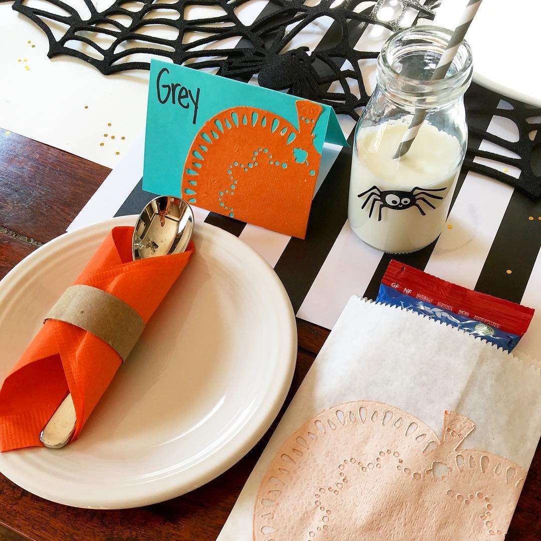 Halloween place setting with an orange napkin, pumpkin name card, and spider milk bottle.