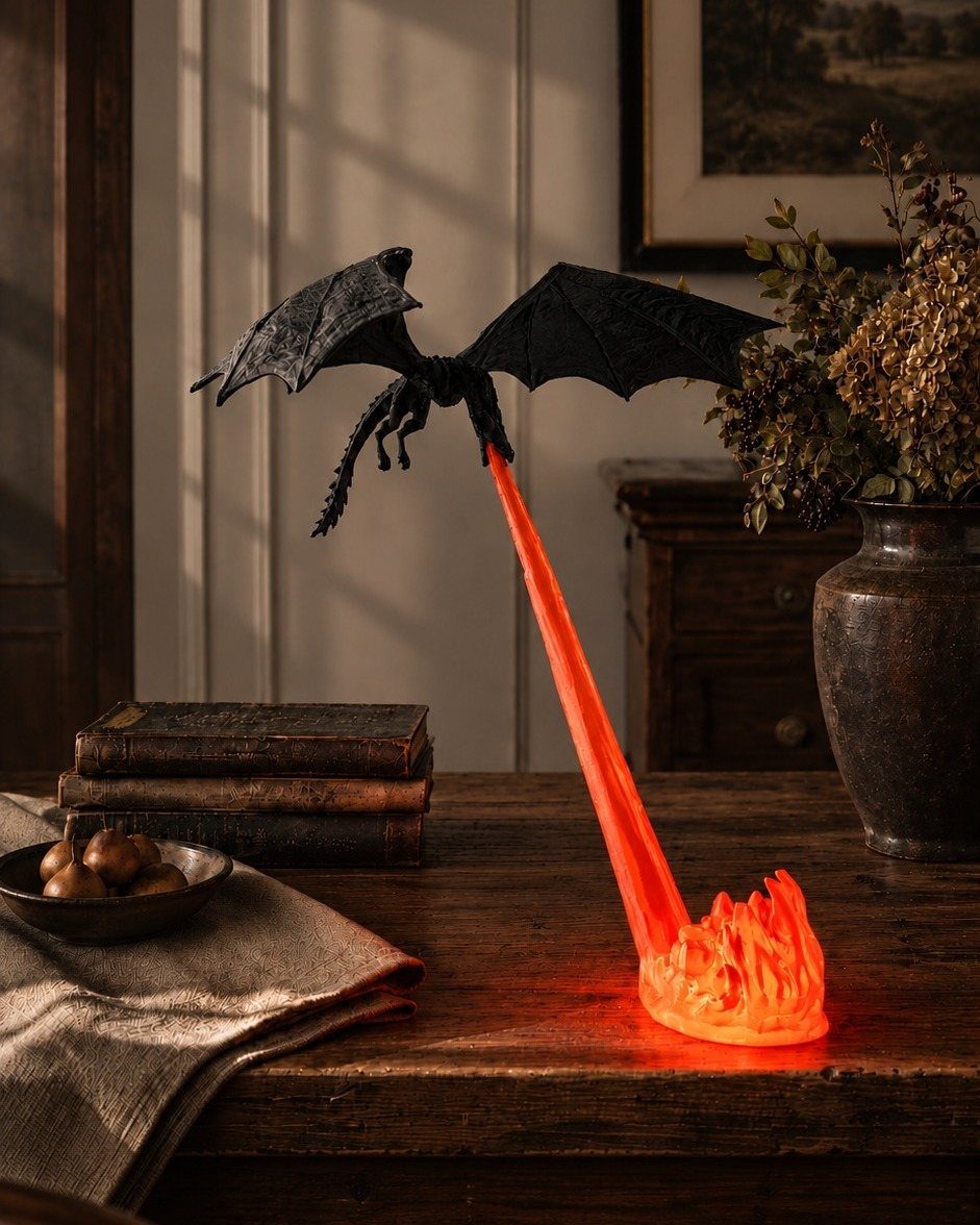 A black dragon figurine perched on a glowing orange flame-shaped light base on a wooden table.