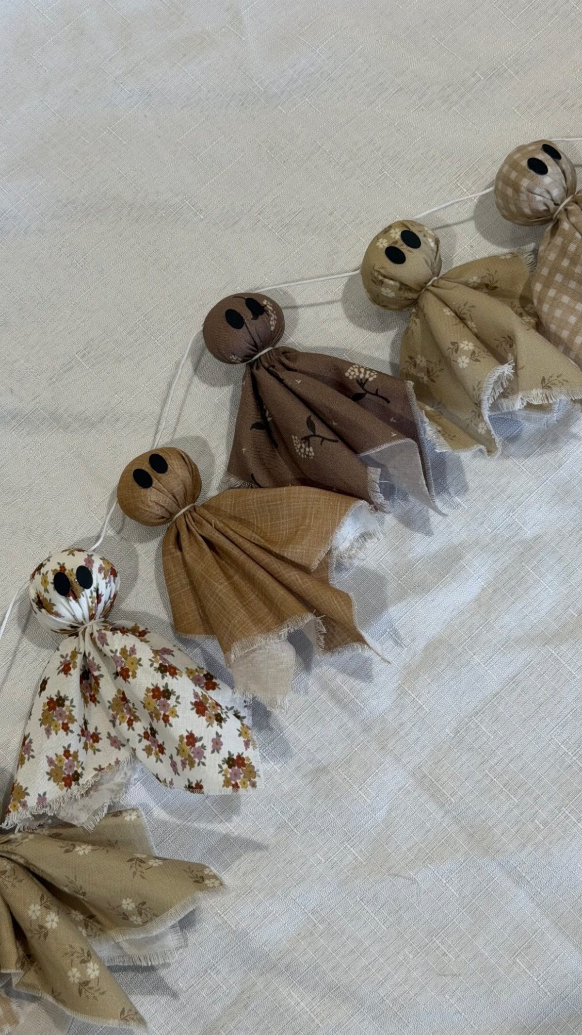 Fabric ghost garland with patterned cloth ghosts strung on a white cord.
