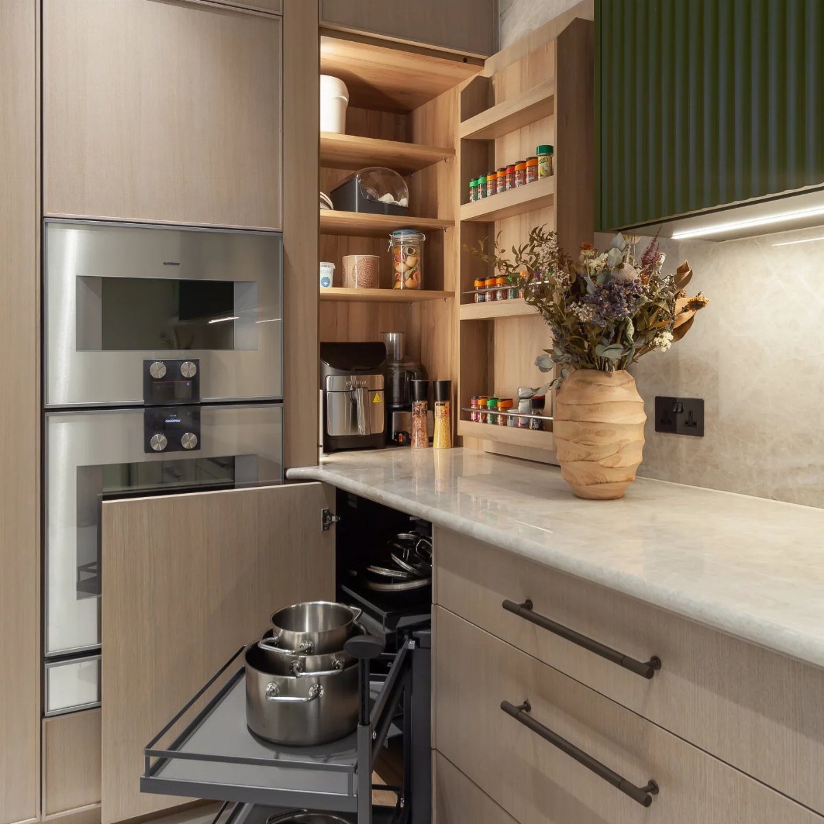 Wooden built-in shelves filled with kitchen canisters and spices above a marble countertop.