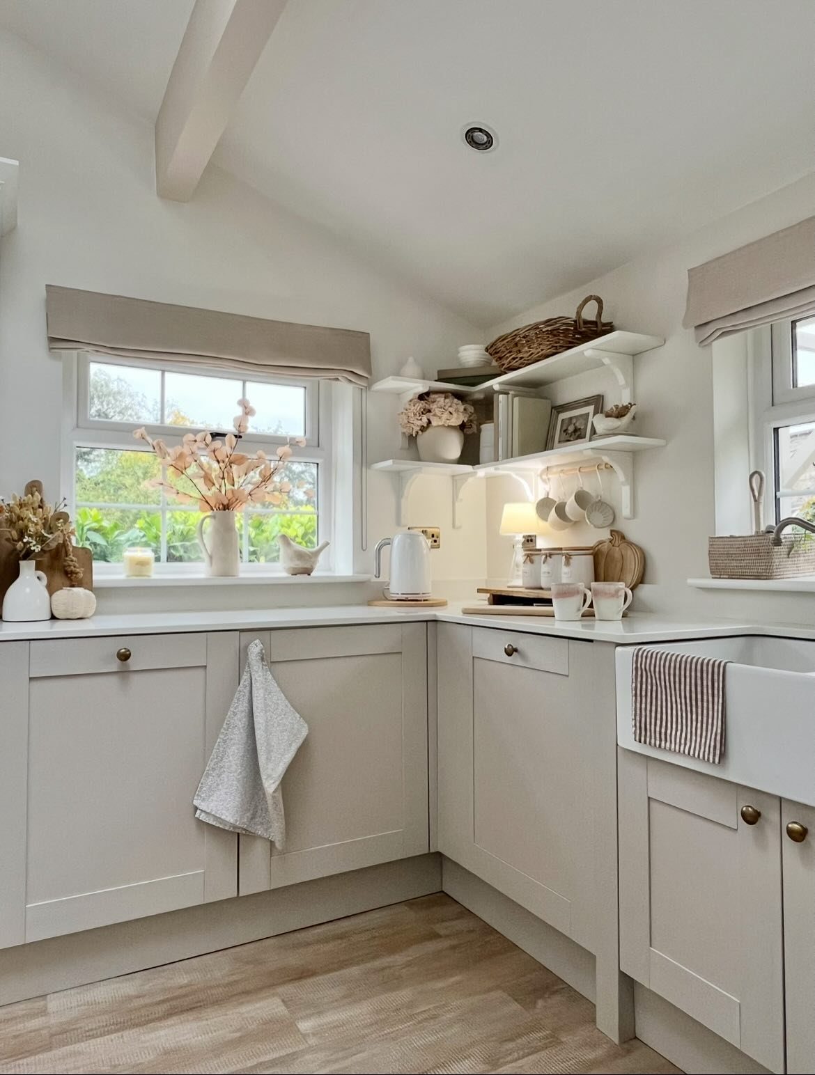 White corner open shelves holding baskets and ceramics in a light grey kitchen.
