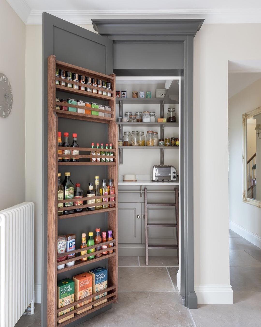 Wooden door-mounted spice rack and white interior pantry shelves filled with various jars and bottles.