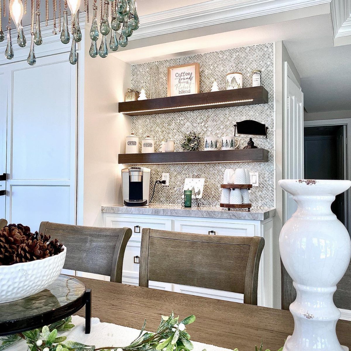 Two dark wood floating shelves with decorative items mounted on a patterned tile backsplash.