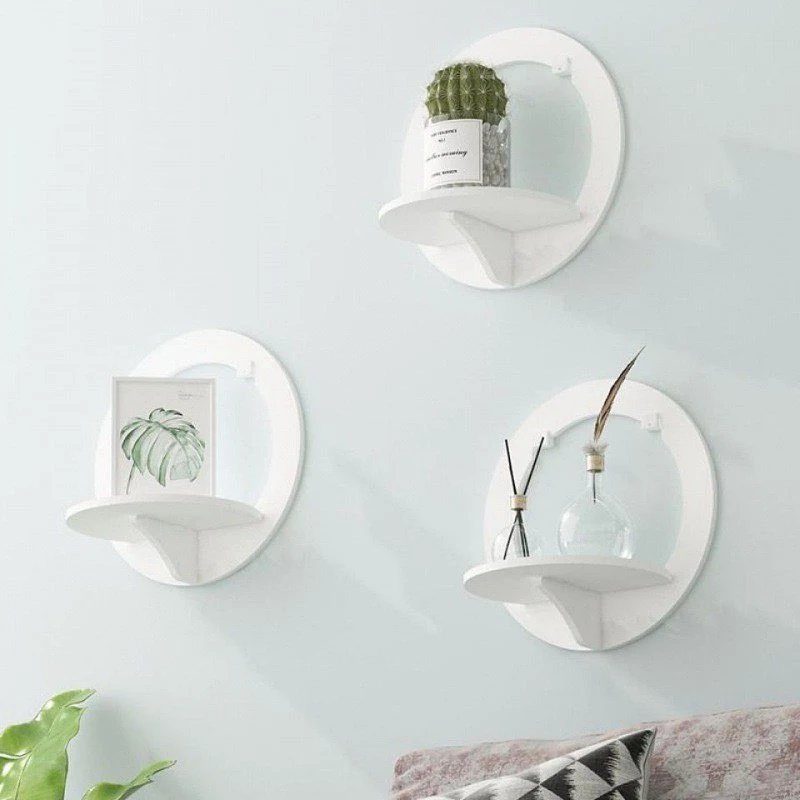 Three white circular floating shelves displaying a cactus, a framed print, and a glass vase.