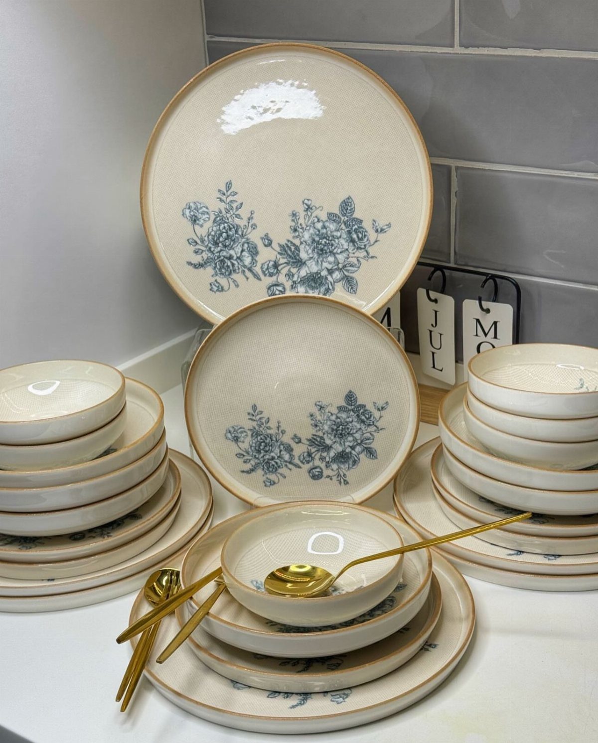 Coordinated cream ceramic plates and bowls with blue floral patterns and gold utensils.