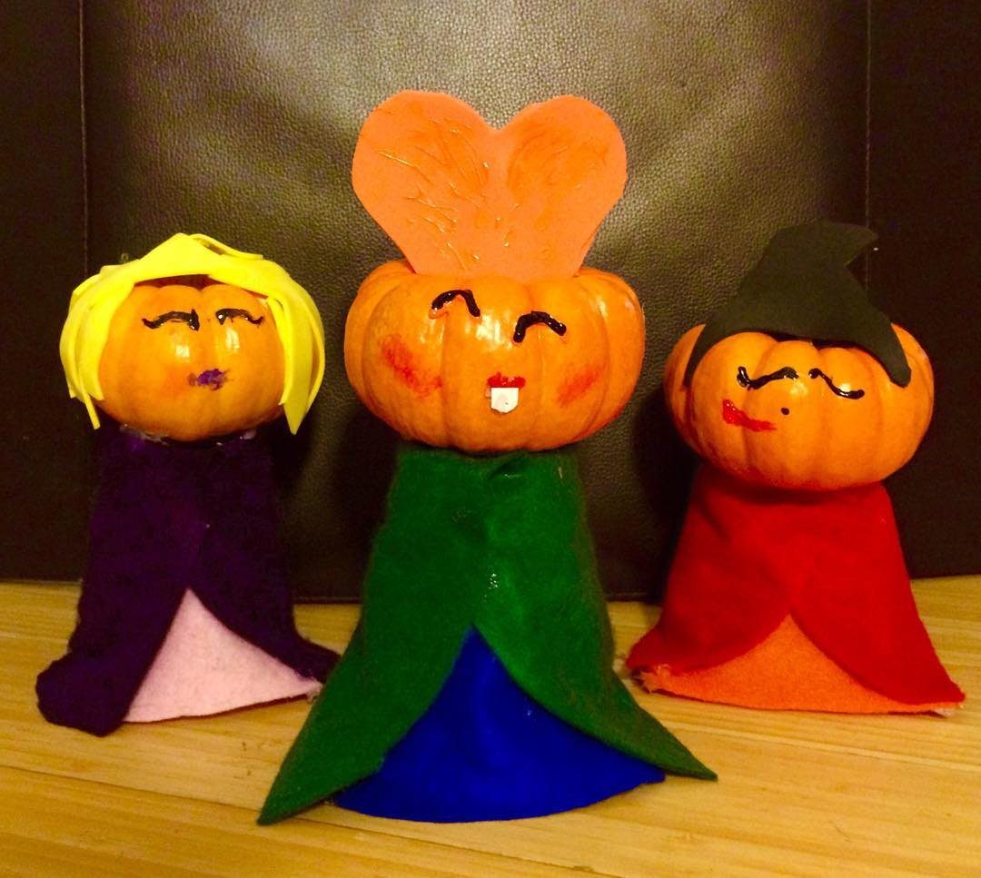 Three decorated pumpkins dressed in colorful fabric capes representing the Sanderson Sisters.