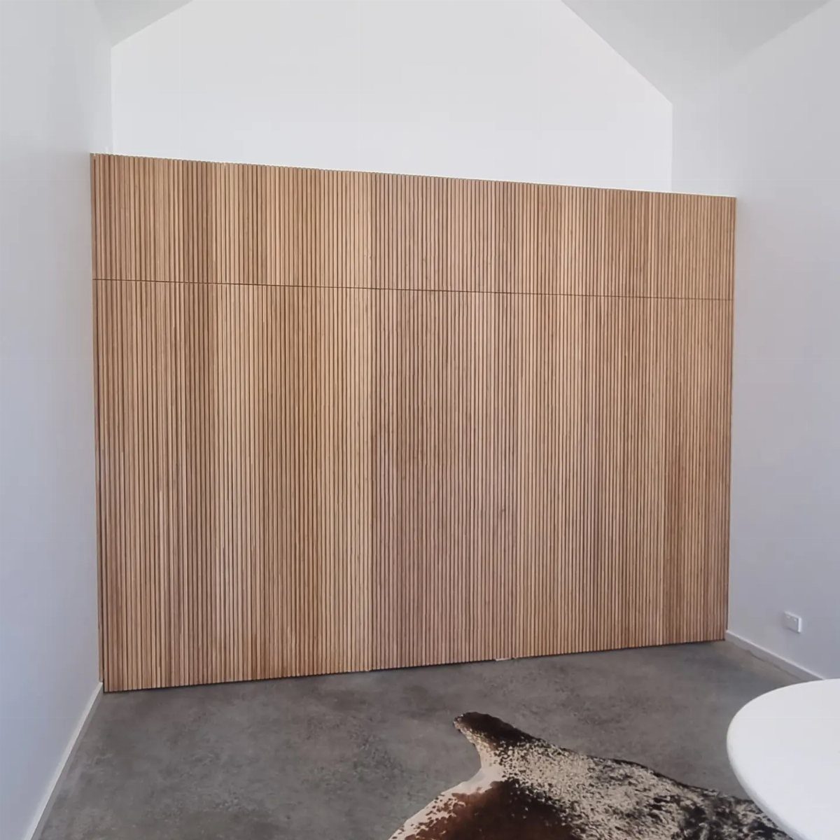 Vertical light wood slat wall covering a large section of a white room.