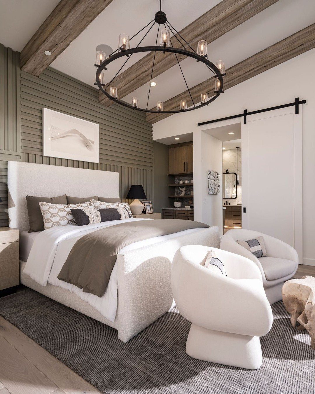 Modern bedroom with white furniture, grey bedding, and a large black circular chandelier.