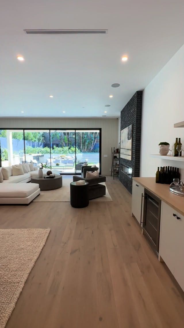 Spacious living room with light wood floors, white sectional sofa, and large glass doors.