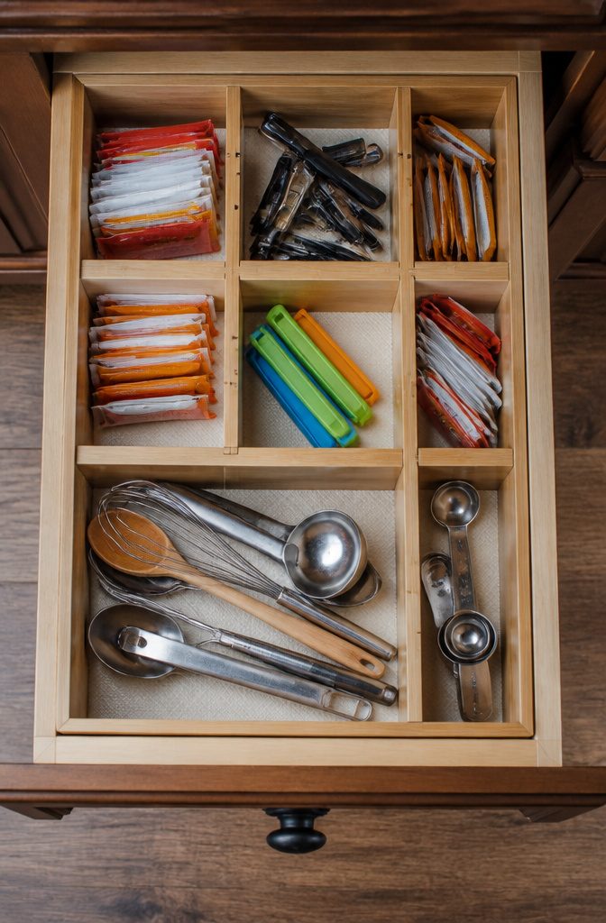 A shallow pantry drawer organized with adjustable dividers for small items.