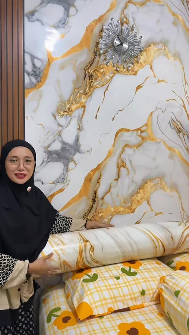Woman holding a roll of marble patterned wallpaper against a matching marble accent wall.