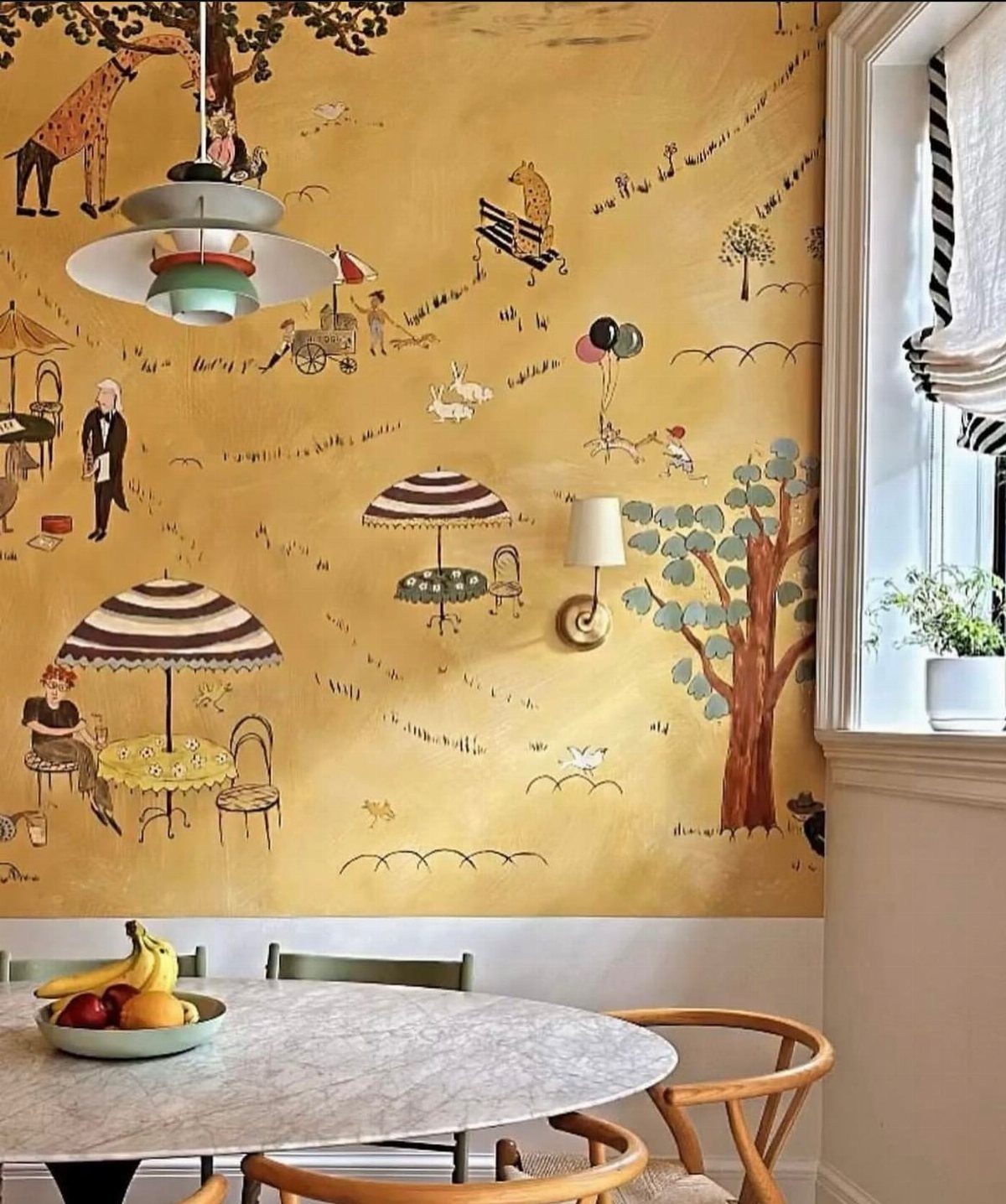 Whimsical mustard yellow wallpaper with illustrated giraffes and umbrellas in a dining room.