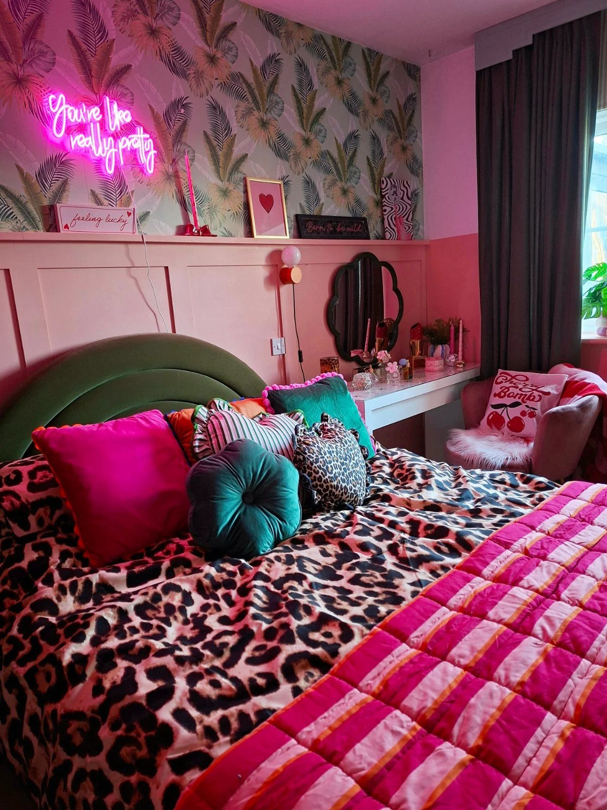 Leopard print bedding on a bed with colorful accent pillows and a green headboard.