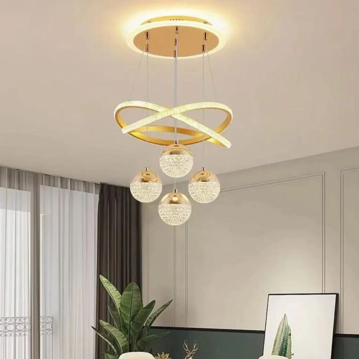 Modern gold chandelier with glowing rings and four crystal sphere pendant lights hanging from the ceiling.