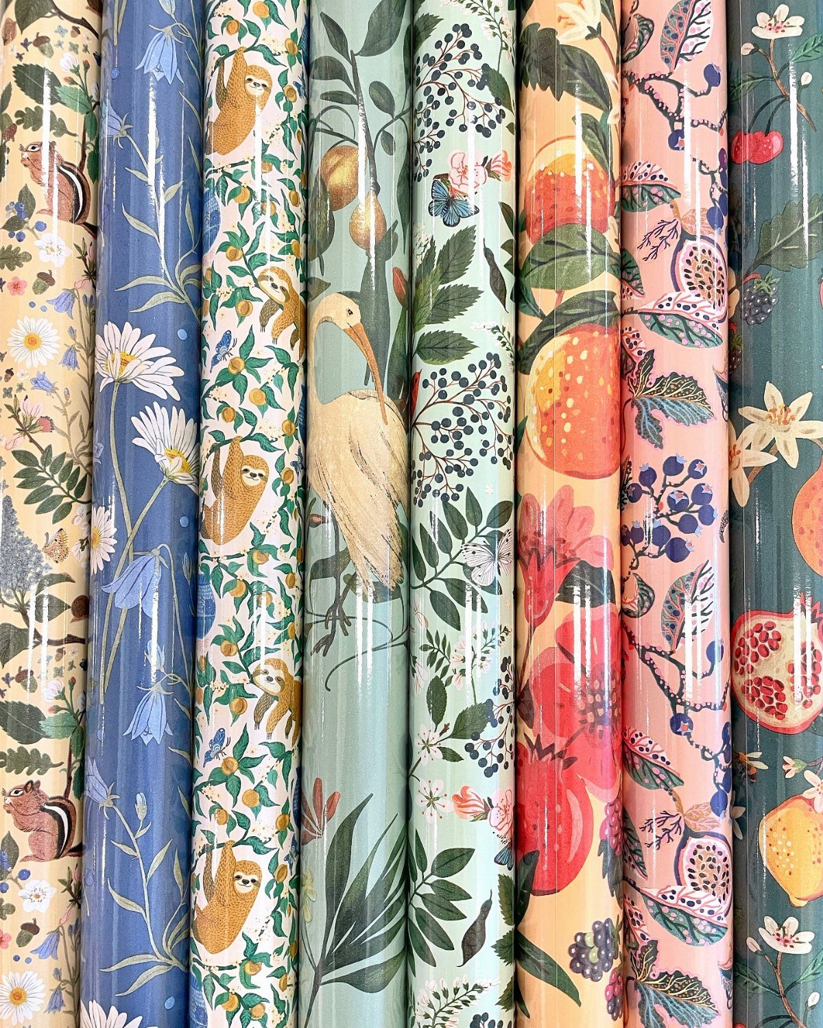 Multiple rolls of colorful patterned wrapping paper with floral and bird designs standing vertically.