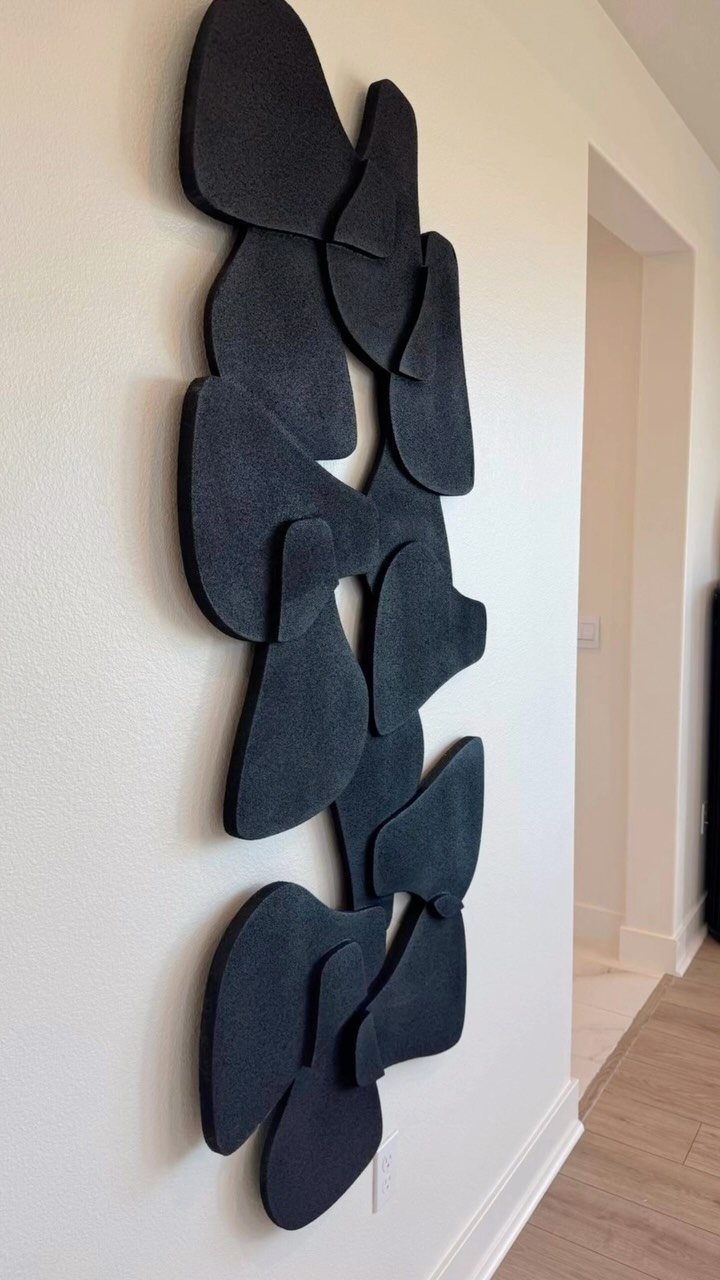 Large black organic sculptural art pieces mounted vertically on a white wall.