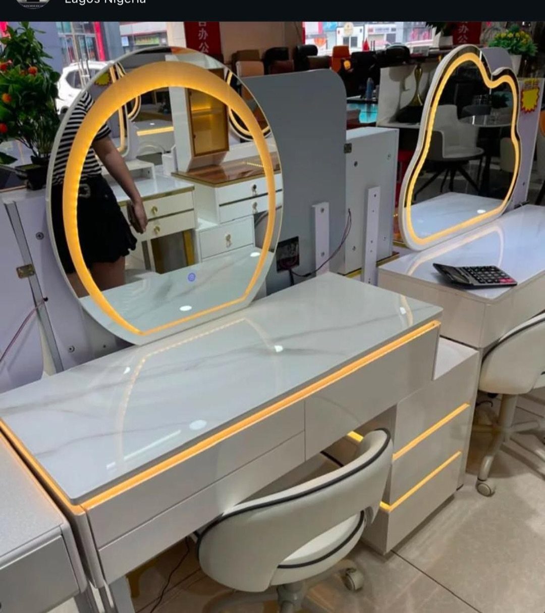 Two white modern dressing vanities with marble tops and circular LED lighted mirrors.