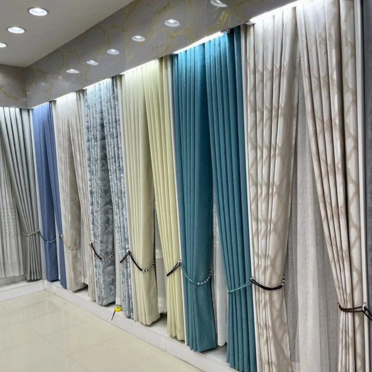 Various colorful drapes and curtains displayed in a showroom with decorative tie-backs.