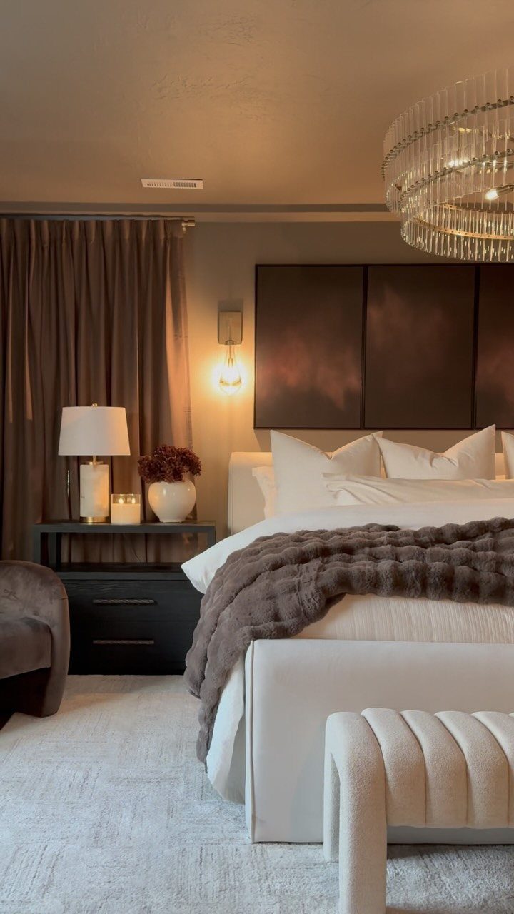 A layered bed with white linens and a brown fur throw in a luxury bedroom.