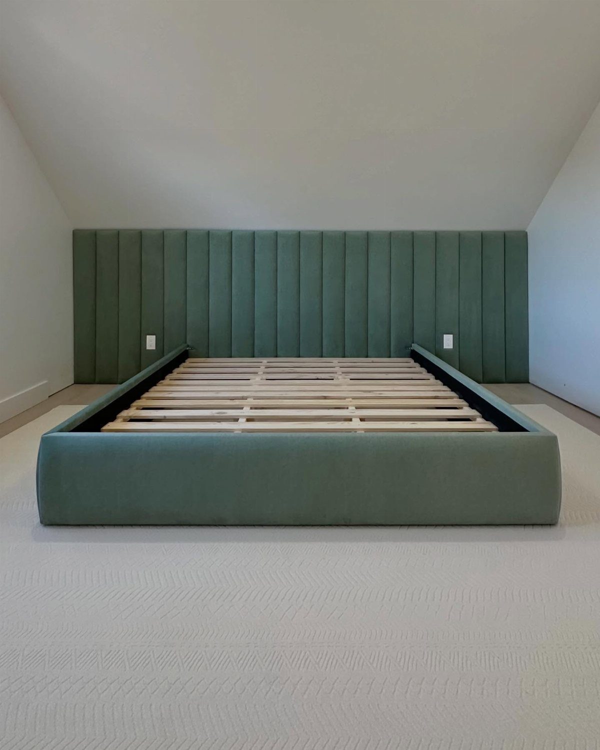 Sage green upholstered bed frame with a matching vertical channel-tufted headboard.