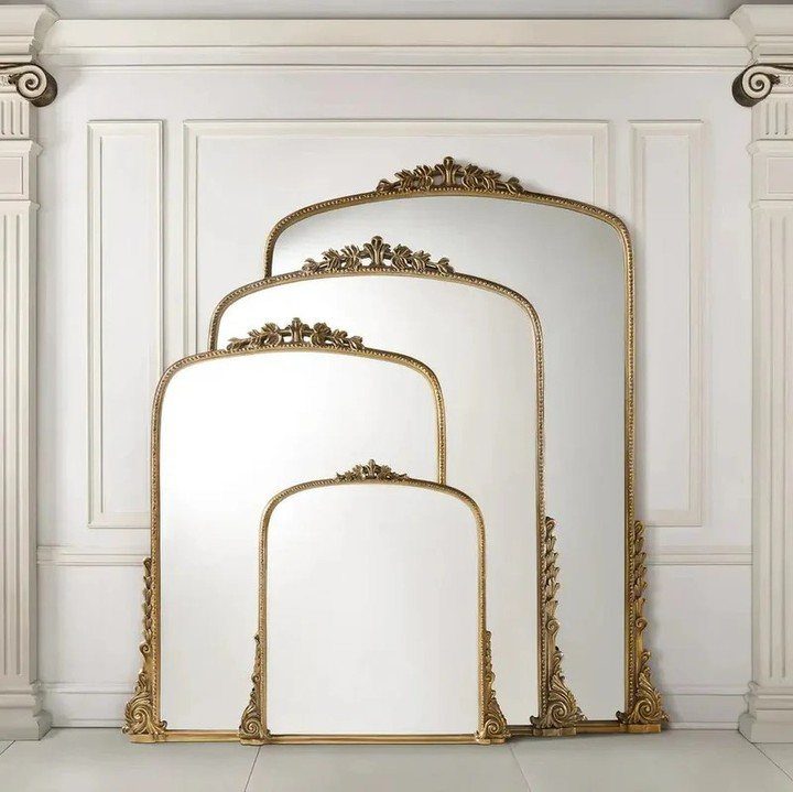 Four gold framed arched mirrors of different sizes arranged against a white wall.