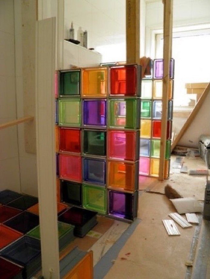 Multi-colored translucent glass blocks arranged in a grid forming a vibrant room partition.