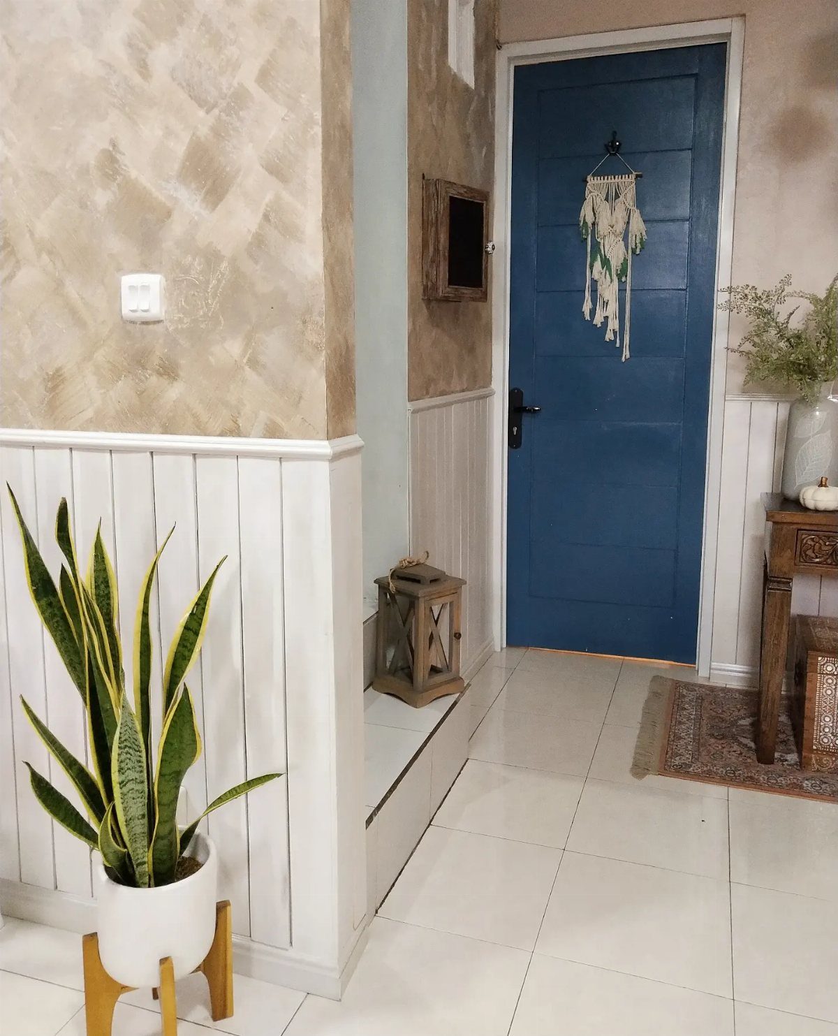 White vertical wainscoting half-wall against a textured beige wall in a bright hallway.