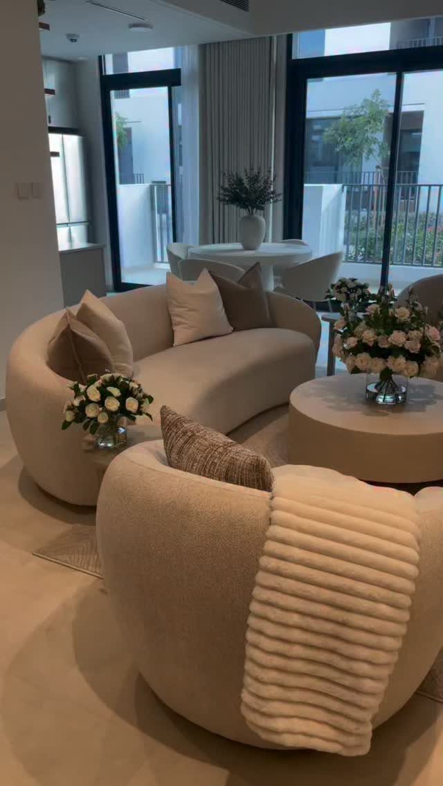 Curved cream sofas and a circular coffee table in a bright, modern living room.