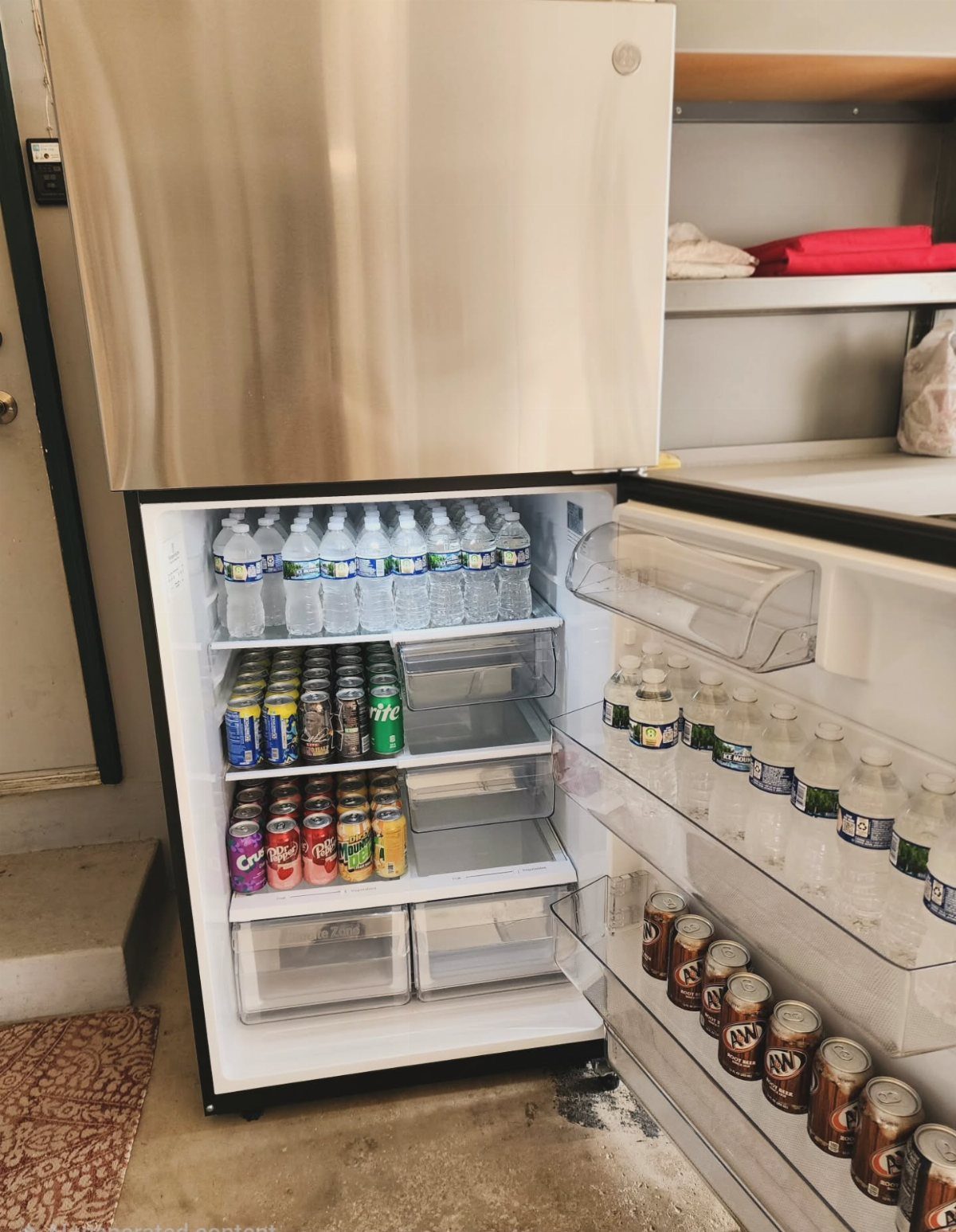 Open mini fridge stocked with bottled water, various canned sodas, and juice boxes.