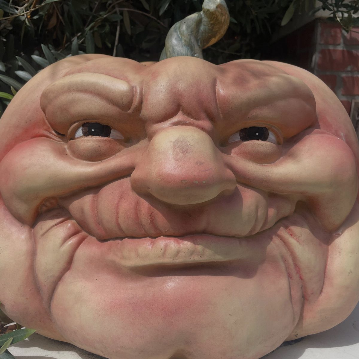 A large sculpted pumpkin decoration with a highly detailed, funny, wrinkled face.