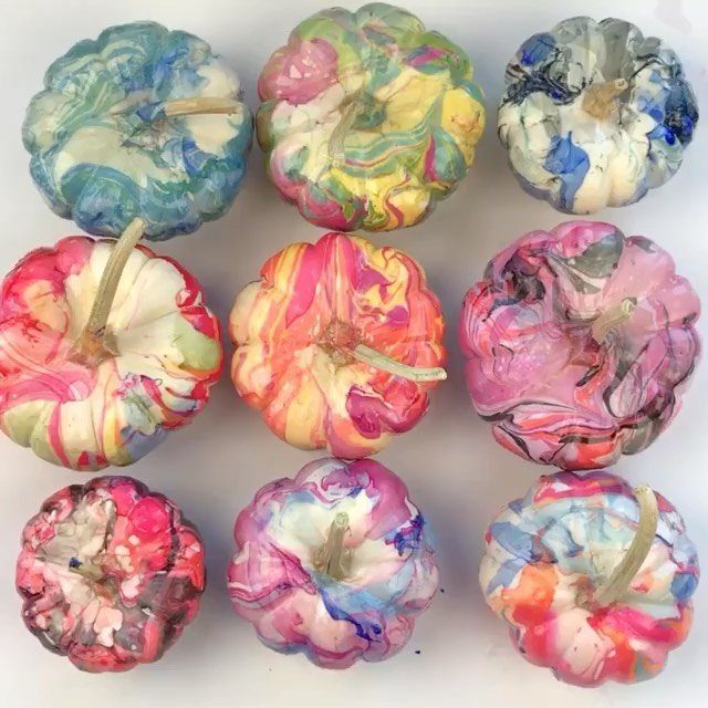 Nine mini pumpkins featuring colorful marbled paint patterns arranged in a grid on white.