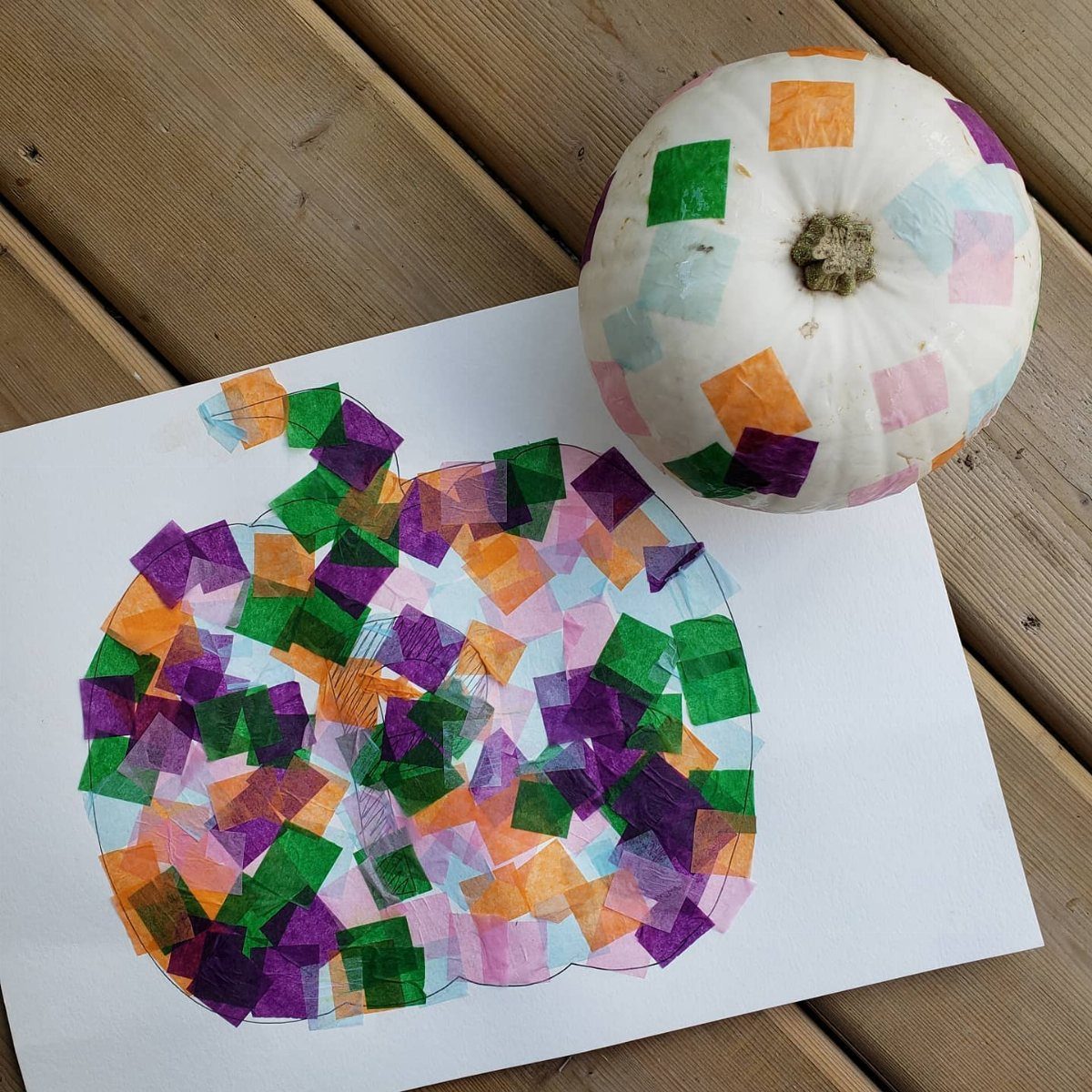 A white mini pumpkin and a paper template decorated with colorful tissue paper squares.