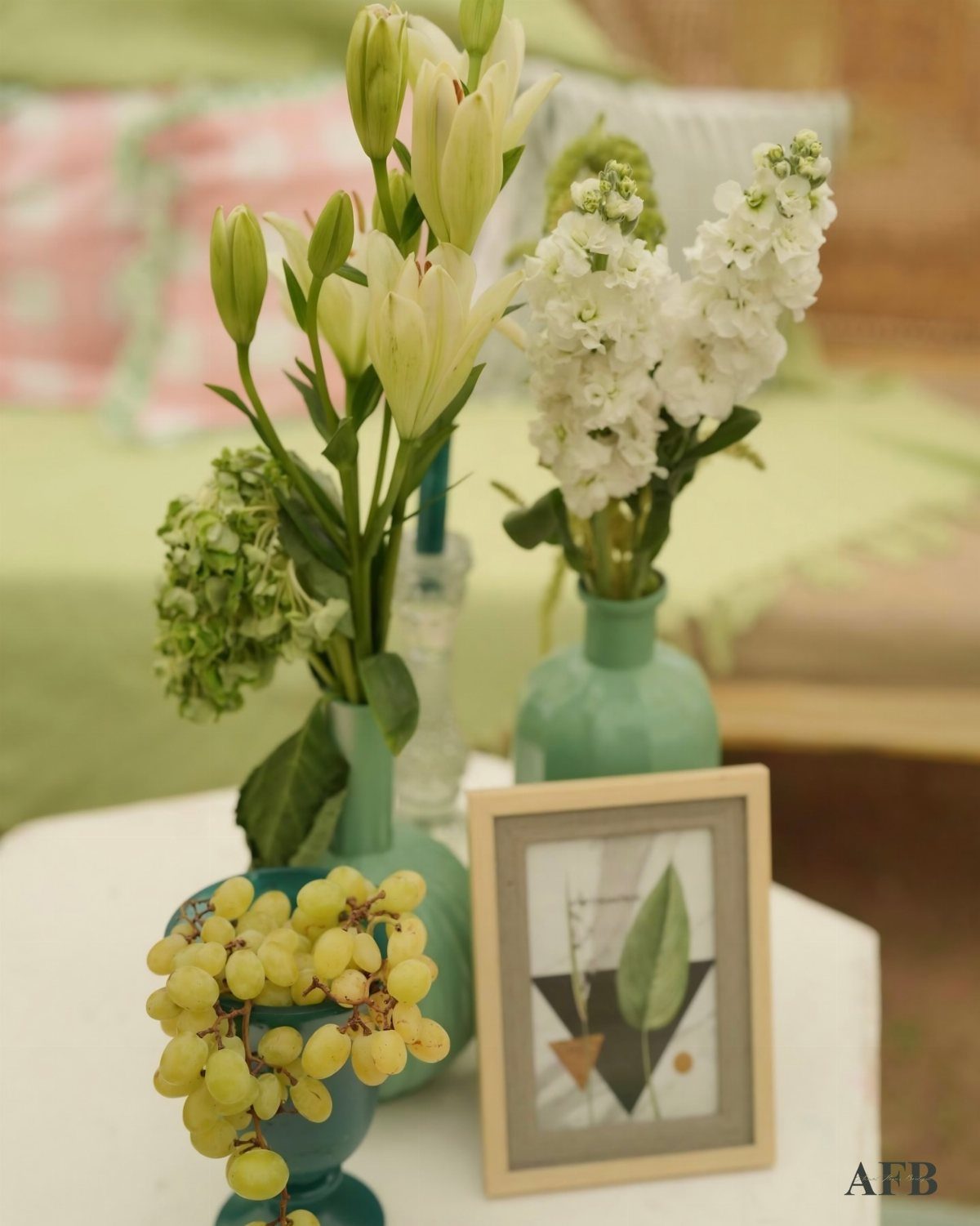 Small floral arrangements with white lilies and stock flowers in light blue vases on a white table.