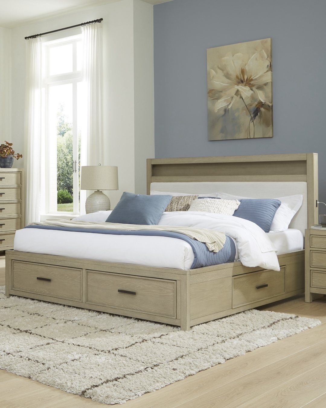 A light wood bed frame featuring integrated storage drawers and blue and white bedding.