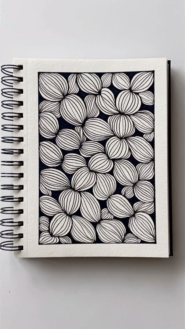 A spiral sketchbook displaying a black and white organic line pattern on a white page.