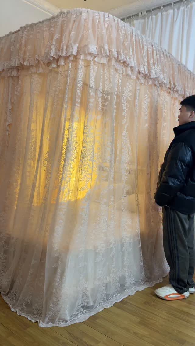 A large canopy bed covered in sheer pink lace fabric glowing from internal lights.