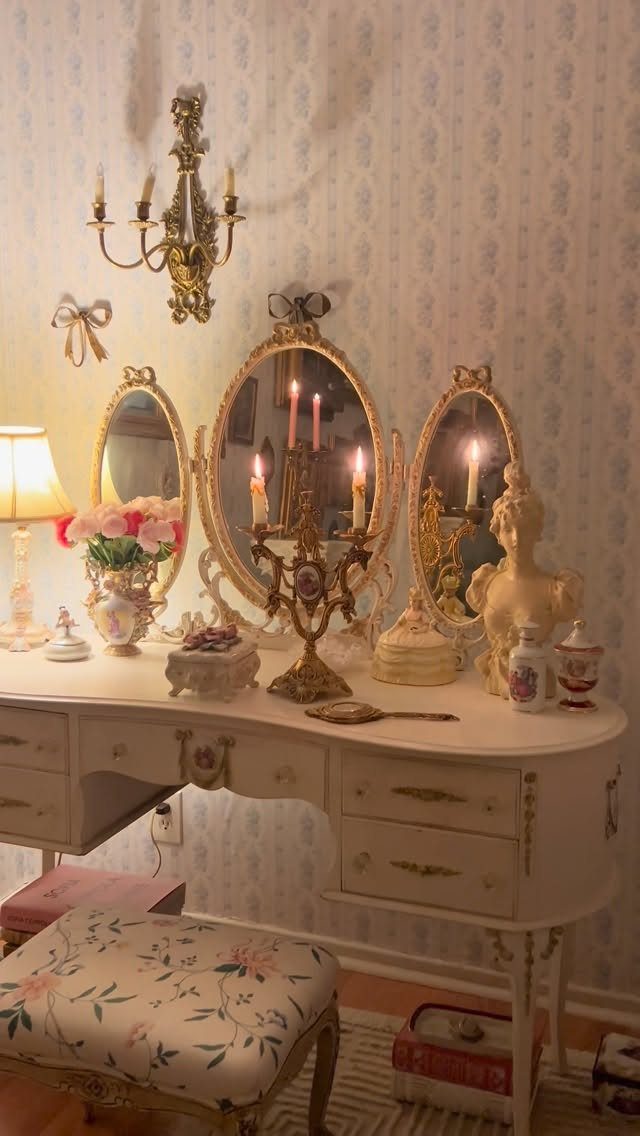 An ornate white vintage vanity table decorated with gold candelabras and antique trinkets.