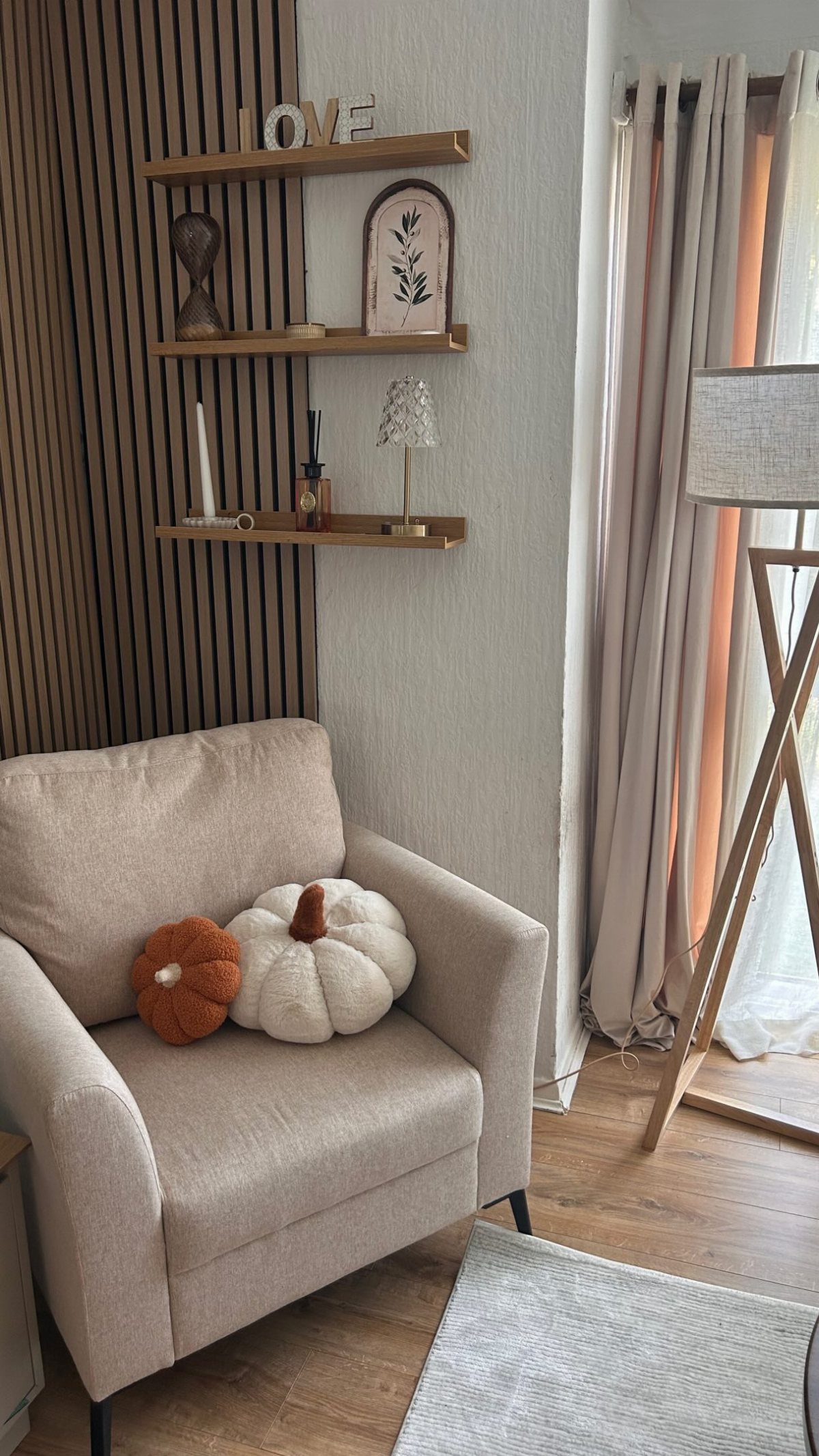 Beige armchair with orange and white pumpkin pillows in a modern cottage corner.