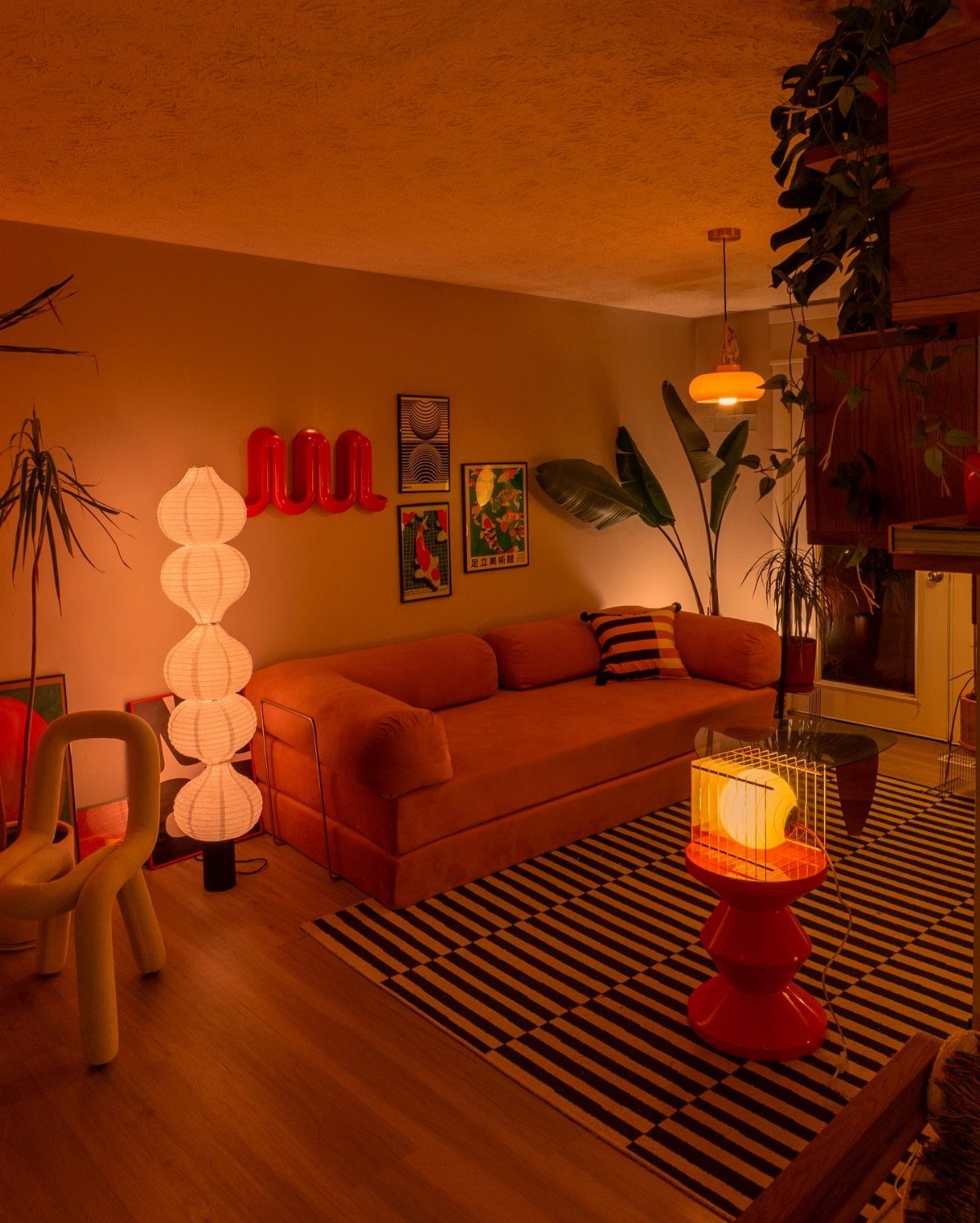 A cozy living room with orange furniture and warm ambient lighting from various lamps.