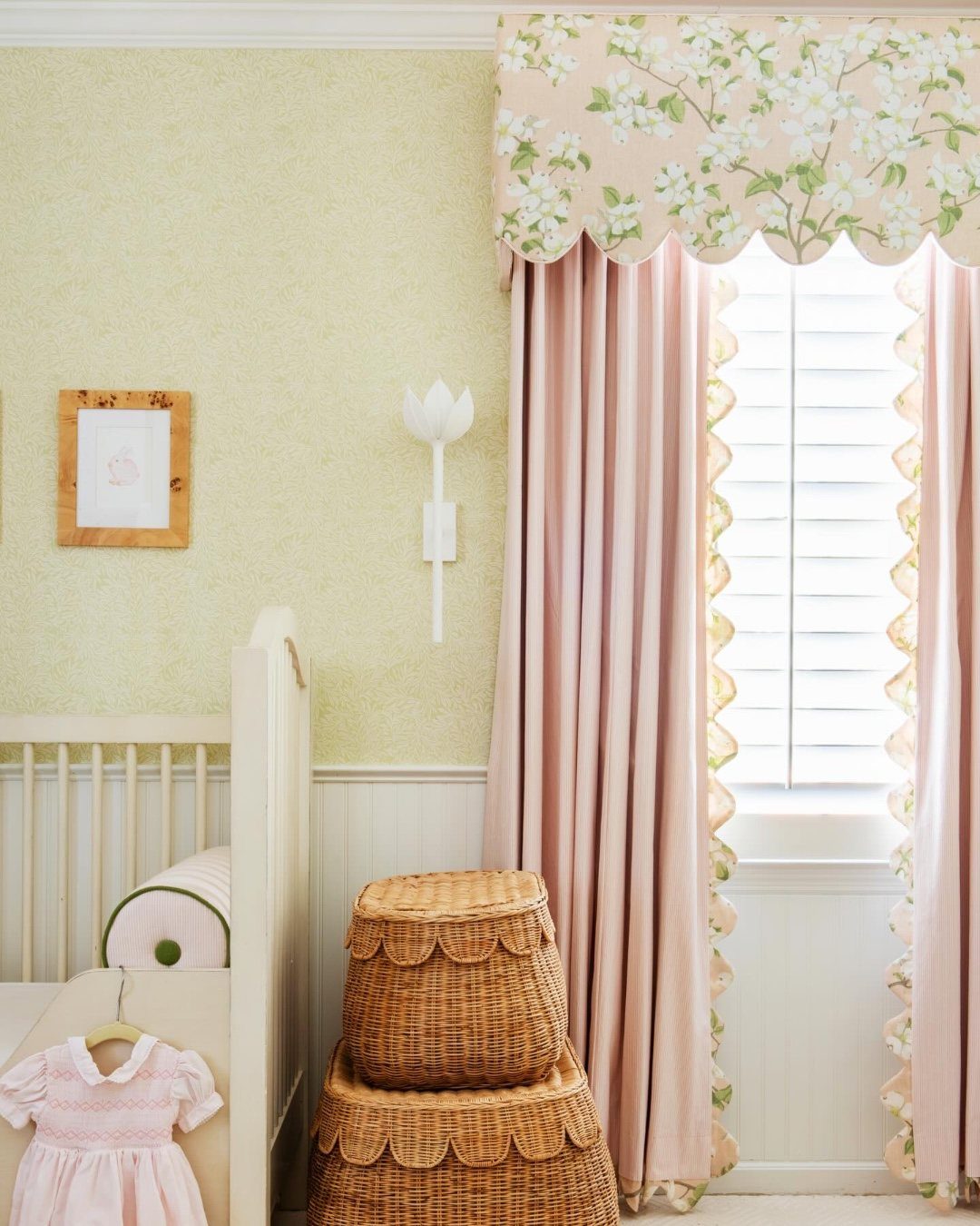 Pink floral scalloped valance and scalloped wicker baskets in a light yellow nursery.