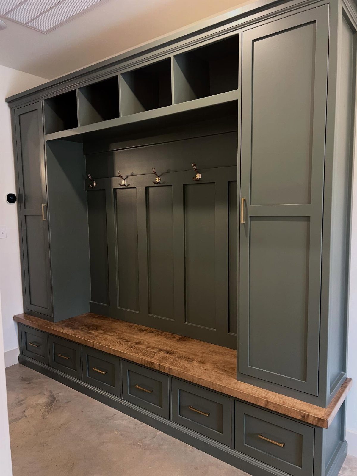 Built-in sage green mudroom unit with a wooden bench and storage drawers.