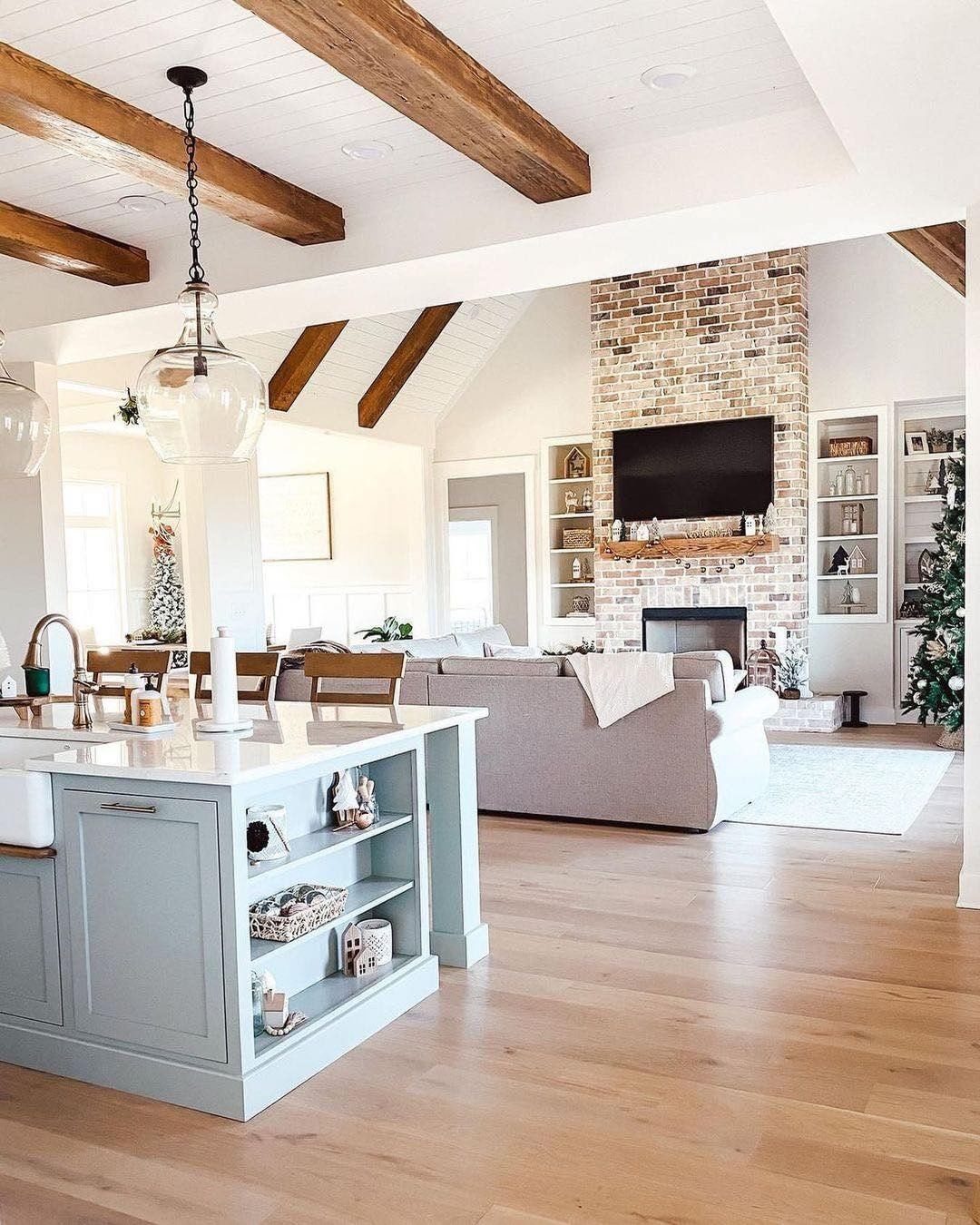 Large wooden beams stretch across a bright, modern farmhouse living room ceiling.