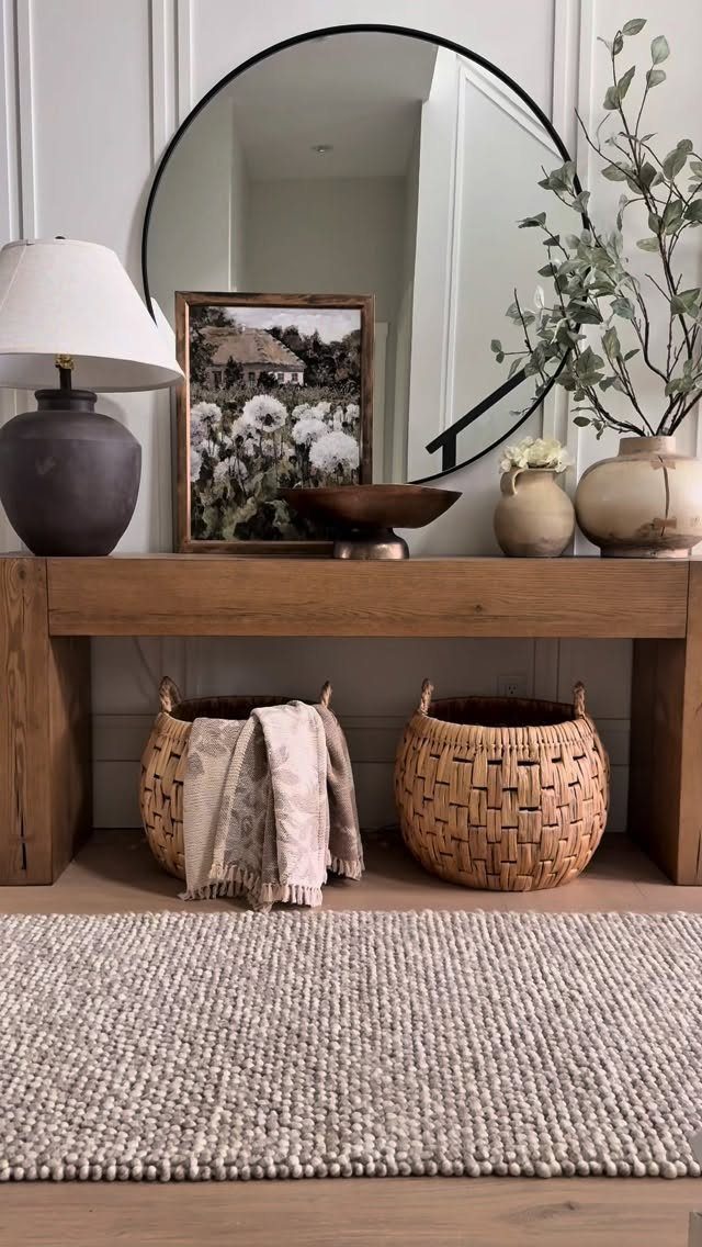 Textured neutral rug in front of a wooden console table with decor and woven baskets.