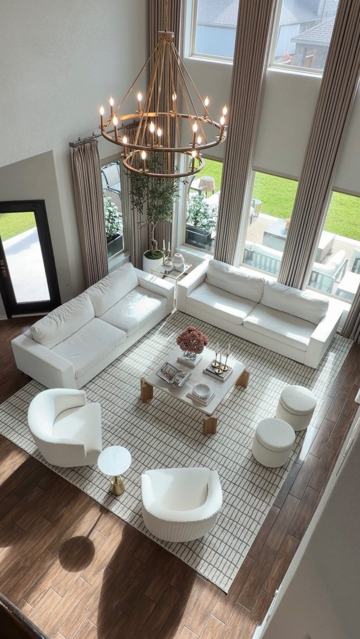 White sofas and armchairs arranged on a large patterned rug in a bright living room.